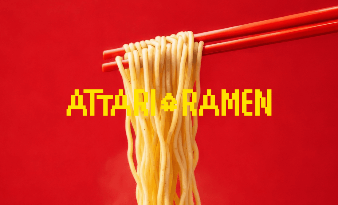 Attari Ramen – żółte logo na tle makaronu uniesionego pałeczkami