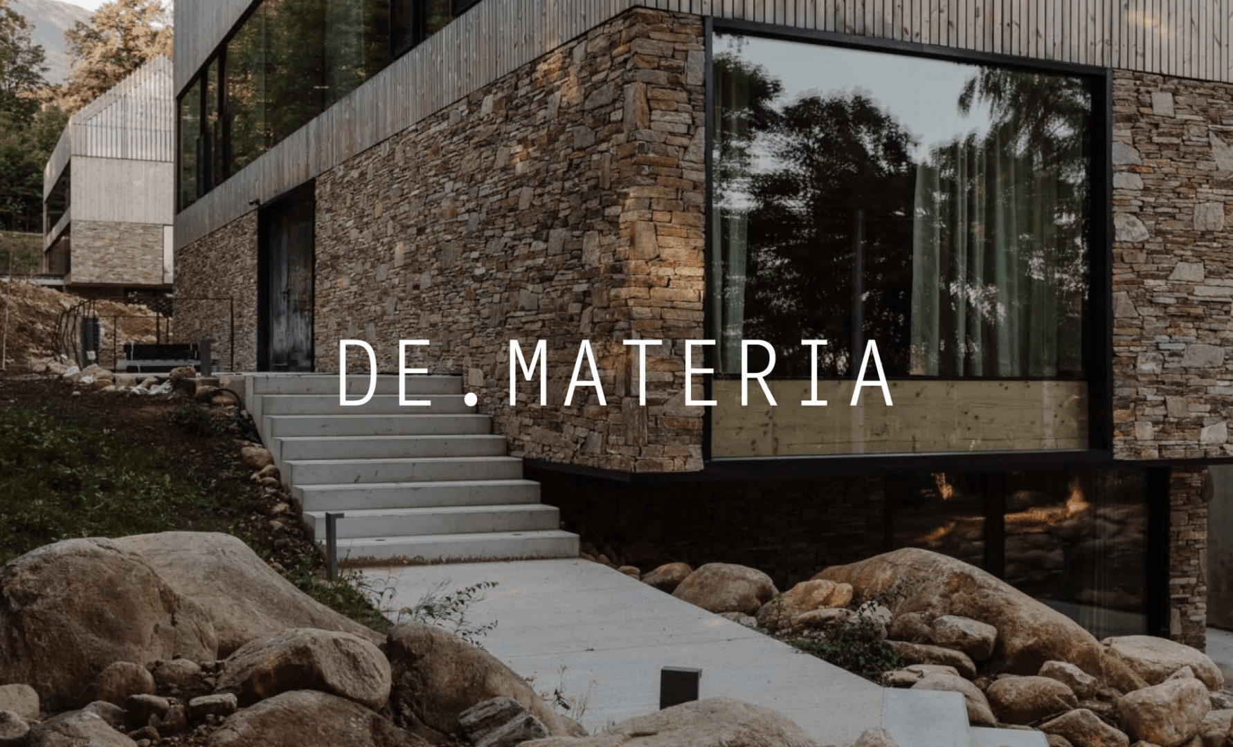 DE.MATERIA – logotyp na tle fotografii domu z kamienną elewacją