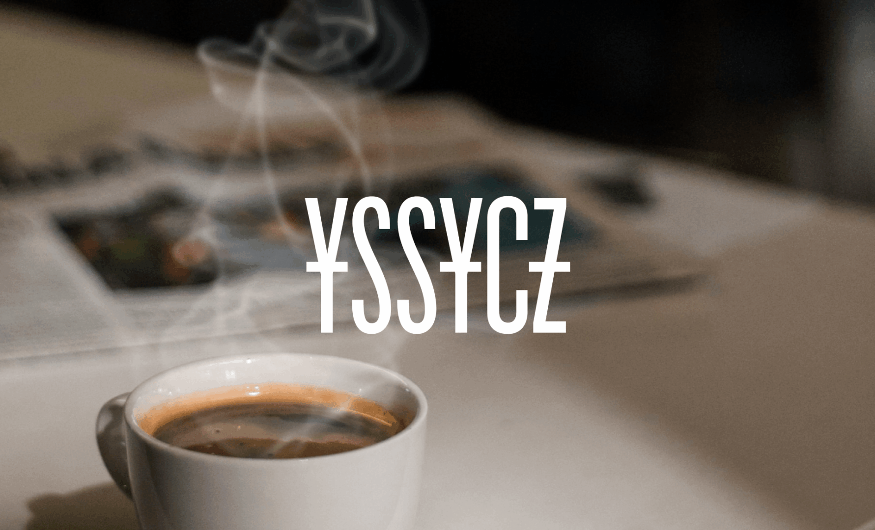 YSSYCZ – logo kawiarni na tle filiżanki kawy